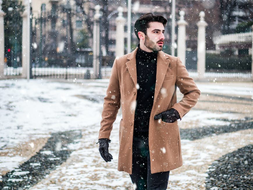 Chico camina por una Turin nevada en invierno en busca de tiendas para comprar. 