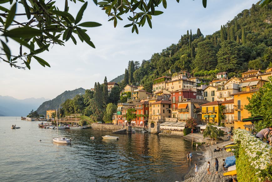 Que ver en Italia. El pueblo de Varenna a orillas del lago de Como. El pueblo tiene muchos edificios coloridos justo al borde del agua y está respaldado por un denso bosque verde.