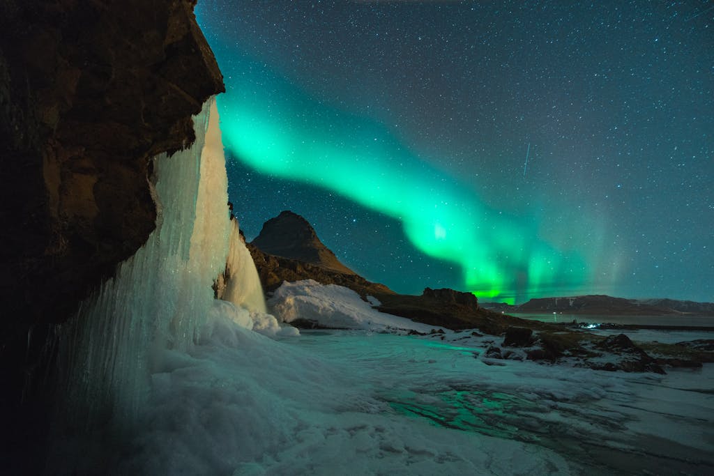 que ver en Europa, Islandia, Stunning view of the Northern Lights over Kirkjufell mountain and frozen waterfall in Iceland. Perfect for nature lovers.