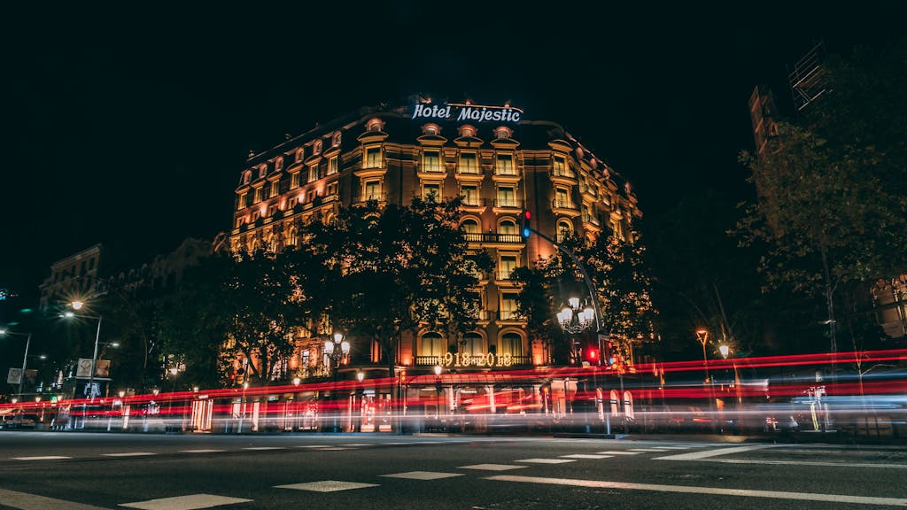 Donde Alojarse en Barcelona Illuminated Hotel Majestic in Barcelona captured at night with vibrant light trails.