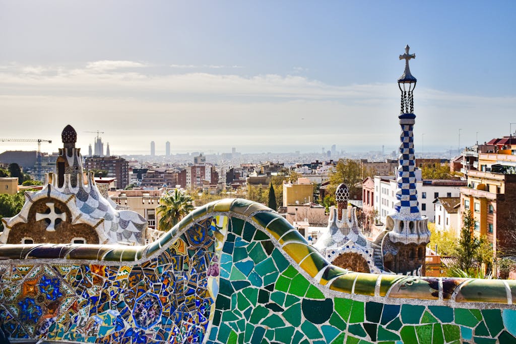 Guia para Viajar a Barcelona; Stunning aerial photograph of Barcelona's distinct city block pattern..View of Barcelona from Park Güell showcasing mosaic architecture and city skyline.